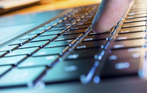 A close-up of a laptop keyboard with a finger pressing down the 'F' key.